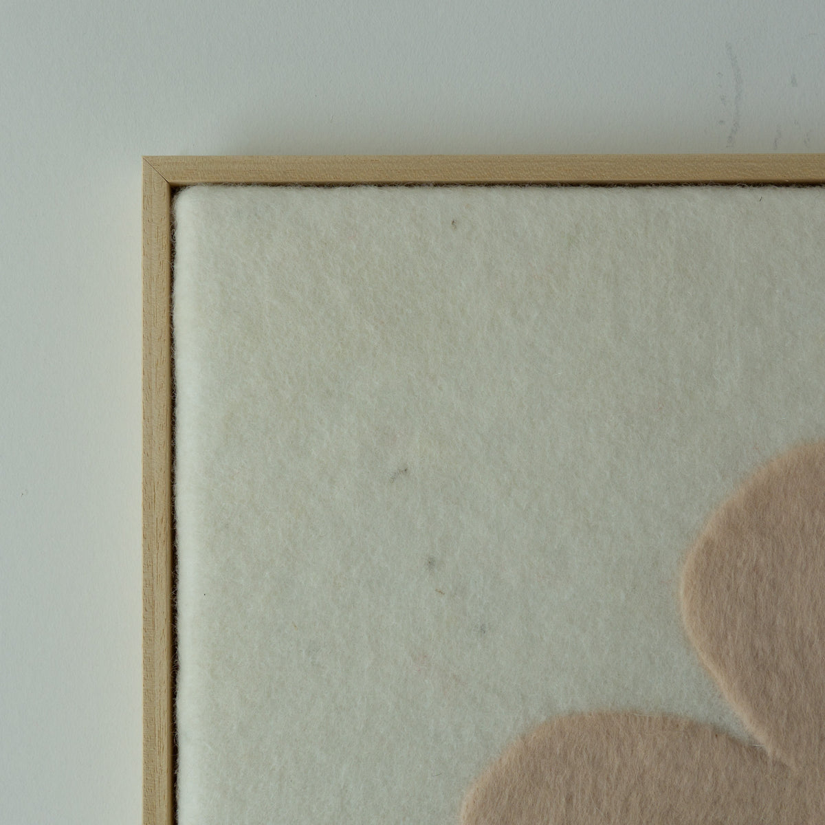 Detail van de lichte wolstructuur en beige vorm in het Stone wandkleed.