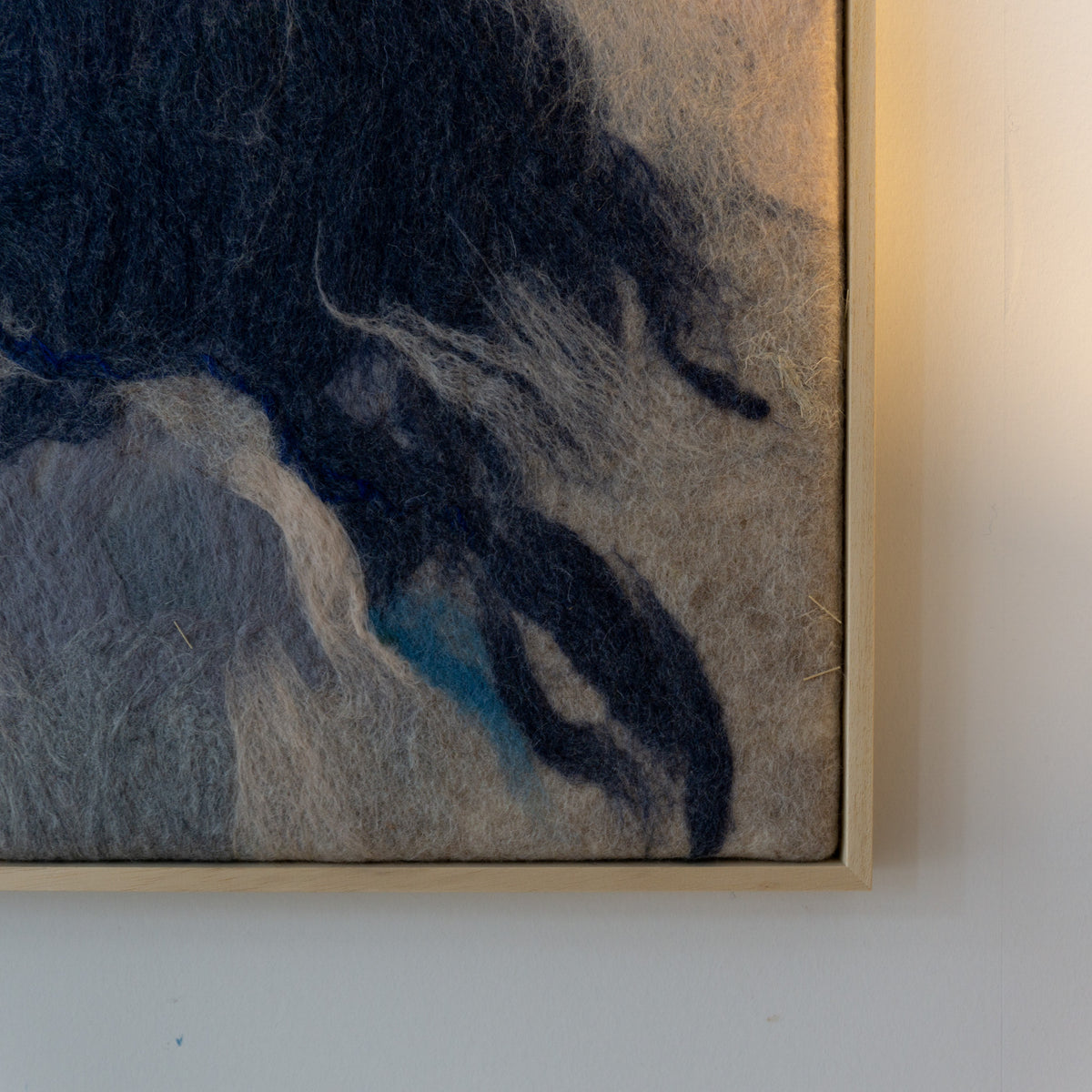 Detail van de donkere en blauwgrijze vormen in het handgemaakte wandkleed.